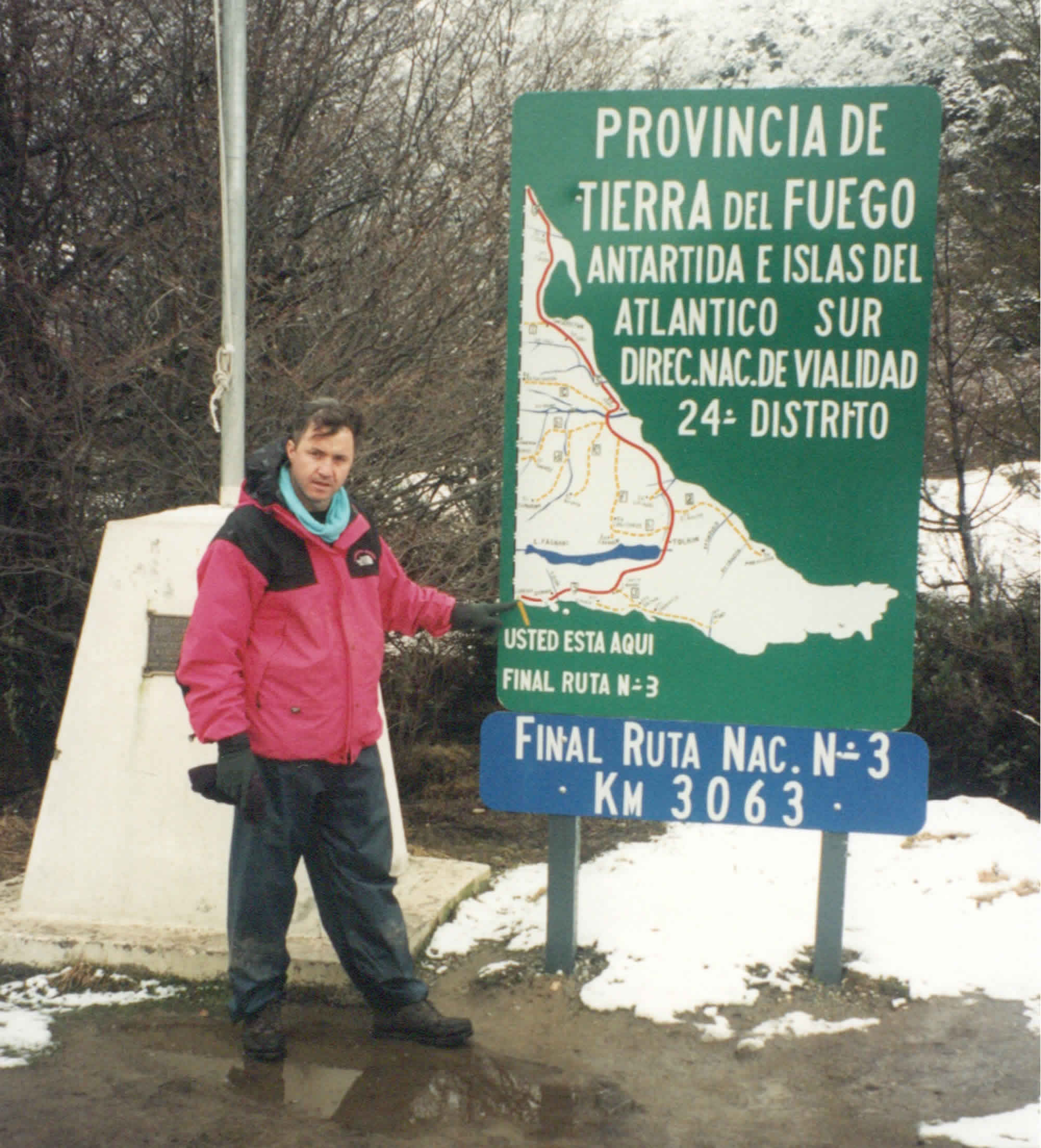 Photo of the author pointing at the end point of the Pan American Highway on a sign in Bahia Lapataia Bay