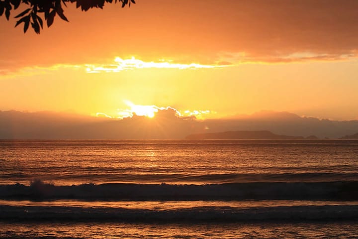 Dramatic photo of the sun rising through clouds over water